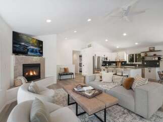 Experience modern living in this stunning open-concept home featuring a cozy fireplace and a sleek, fully-equipped kitchen with a large island.