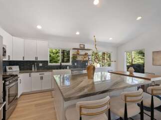 Experience modern living in this stunning kitchen featuring sleek white cabinetry and a striking marble island.
