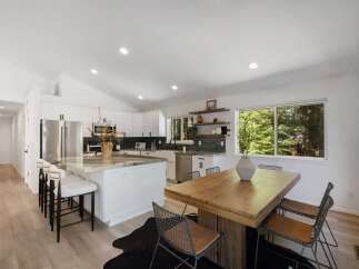 Experience modern living in this stunning kitchen, featuring sleek white cabinetry, a large island with a marble countertop, and stainless steel appliances.