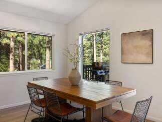 Enjoy dining with a view in this spacious dining room, featuring a large wooden table perfect for gatherings.