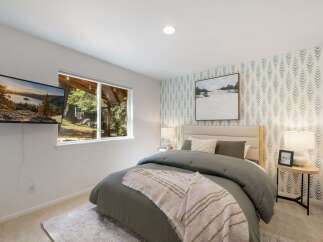 This bedroom offers a serene retreat with a comfortable queen-size bed adorned with a textured duvet and a cozy throw blanket.