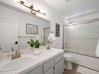 This bright and airy bathroom features a double vanity with modern brass fixtures, perfect for busy mornings.