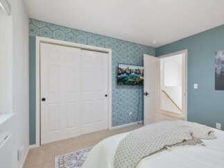 This inviting bedroom features a stylish accent wall with a geometric pattern, complemented by a modern flat-screen TV.