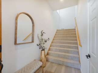 Welcome guests into this inviting entryway featuring a stylish arched mirror and a comfortable bench.