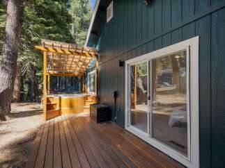 Experience ultimate relaxation in this secluded cabin retreat, featuring a luxurious wooden hot tub nestled under a covered pergola on a spacious deck.