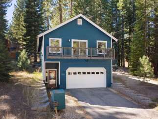 Nestled among tall pine trees, this charming blue home offers a serene mountain retreat.
