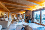 Experience rustic luxury in this stunning mountain chalet living room, featuring a grand stone fireplace and exposed wooden beams.