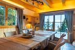 Experience cozy mountain living in this charming dining room, featuring a rustic wooden table set for a meal and surrounded by comfortable wicker chairs.