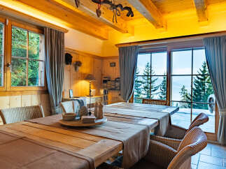 Experience cozy mountain living in this charming dining room, featuring a rustic wooden table set for a meal and surrounded by comfortable wicker chairs.
