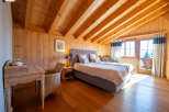 Experience rustic charm and modern comfort in this beautifully appointed bedroom, featuring warm wooden paneling and a vaulted ceiling with exposed beams.