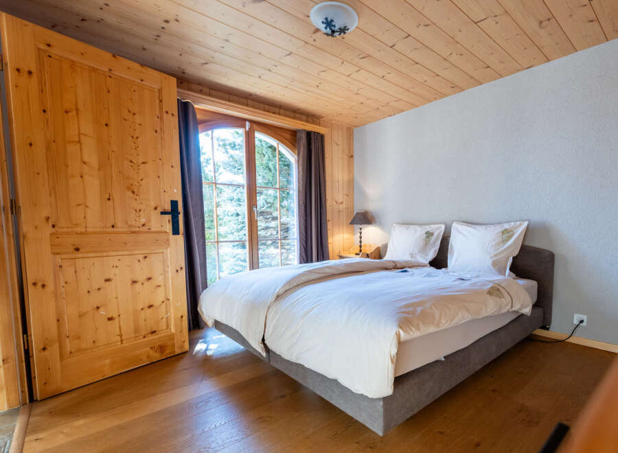 Experience rustic charm in this cozy bedroom featuring a comfortable bed adorned with crisp white linens and decorative pillows.