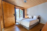 Experience rustic charm in this cozy bedroom featuring a comfortable bed adorned with crisp white linens and decorative pillows.
