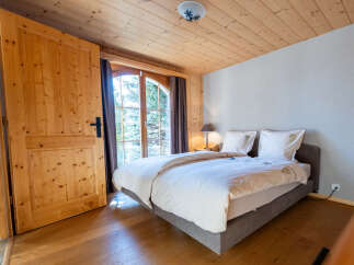Experience rustic charm in this cozy bedroom featuring a comfortable bed adorned with crisp white linens and decorative pillows.