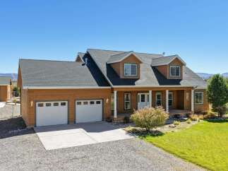 Discover this charming home featuring a warm wood exterior and a welcoming covered front porch, perfect for enjoying the serene surroundings.