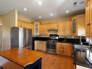 Discover this charming kitchen featuring light wood cabinetry and sleek black granite countertops.