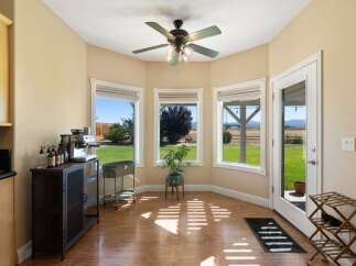Enjoy your morning coffee with a view in this charming sunroom, featuring a dedicated coffee station and large windows overlooking a lush green backyard.