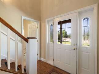 Step into a welcoming entryway featuring a grand double door with decorative glass panels, offering a glimpse of the scenic outdoors.