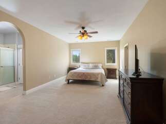 Step into this spacious master suite, featuring a king-sized bed adorned with decorative pillows and a cozy quilt.