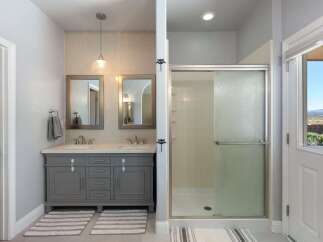 This spacious bathroom features a double vanity with ample counter space and storage, complemented by two elegant mirrors and a modern pendant light.