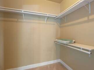 This spacious walk-in closet offers ample storage with its dual-level shelving and hanging rods.