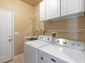 This laundry room features a convenient utility sink and ample storage with overhead cabinets.