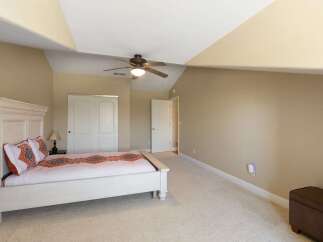 Discover this inviting bedroom featuring a spacious white bed with decorative pillows and a patterned quilt.