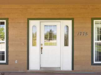 Welcome to this charming home featuring a classic white front door with glass accents, flanked by two arched sidelights and a central window.