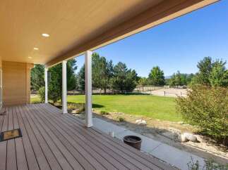 Enjoy the serene country lifestyle from this charming covered porch, offering a perfect vantage point of the expansive green lawn and mature trees.