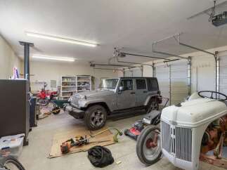 This spacious garage offers ample storage and parking for multiple vehicles, including a Jeep, tractor, and motorcycle.