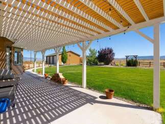 Enjoy outdoor living under this expansive white pergola, offering ample shade and a charming ambiance with string lights.