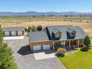 Discover this stunning property featuring a spacious main house with a welcoming wrap-around porch and multiple dormer windows, complemented by a detached three-car garage and an additional two-car garage.