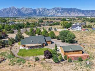 Discover this expansive property featuring a charming main residence with a covered porch, perfect for enjoying the stunning mountain views.