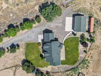 Discover this stunning property featuring a spacious main house with a dark green roof and an attached garage, complemented by a separate building with a matching roof and a unique orange shipping container addition.