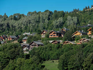 Discover charming chalets nestled on a lush green mountainside, offering breathtaking views and a serene alpine escape.