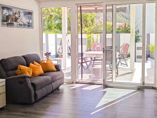 Step into this inviting living space featuring a comfortable dark grey sofa adorned with vibrant orange cushions.