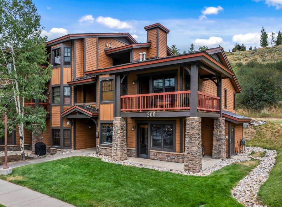 Experience mountain living in this stunning multi-story condo, featuring a warm wood exterior and stone accents.