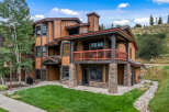Experience mountain living in this stunning multi-story condo, featuring a warm wood exterior and stone accents.