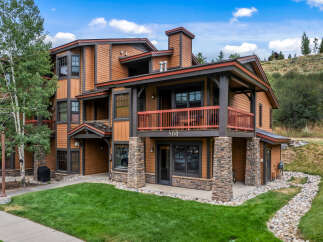 Experience mountain living in this stunning multi-story condo, featuring a warm wood exterior and stone accents.