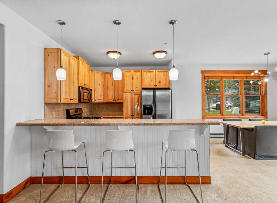 This inviting kitchen features warm wood cabinetry and a granite-topped breakfast bar, perfect for casual dining.