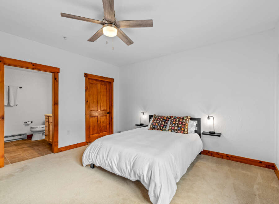 Experience cozy comfort in this charming bedroom, featuring a plush queen-size bed adorned with vibrant, decorative pillows.