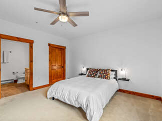 Experience cozy comfort in this charming bedroom, featuring a plush queen-size bed adorned with vibrant, decorative pillows.