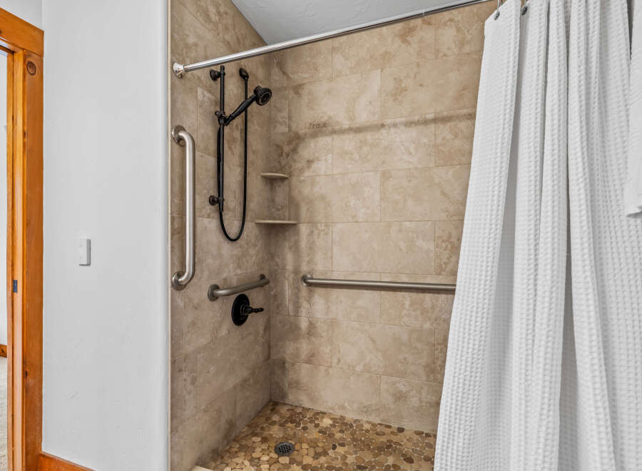 Experience accessible luxury in this beautifully designed bathroom, featuring a spacious walk-in shower equipped with multiple grab bars for enhanced safety and convenience.