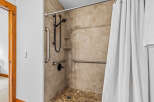 Experience accessible luxury in this beautifully designed bathroom, featuring a spacious walk-in shower equipped with multiple grab bars for enhanced safety and convenience.