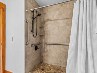 Experience accessible luxury in this beautifully designed bathroom, featuring a spacious walk-in shower equipped with multiple grab bars for enhanced safety and convenience.
