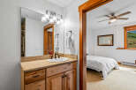 This charming bathroom features a granite countertop vanity with a wooden cabinet base, complemented by a large mirror with a vanity light fixture.
