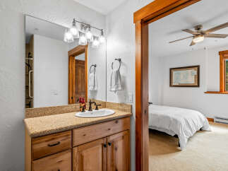 This charming bathroom features a granite countertop vanity with a wooden cabinet base, complemented by a large mirror with a vanity light fixture.