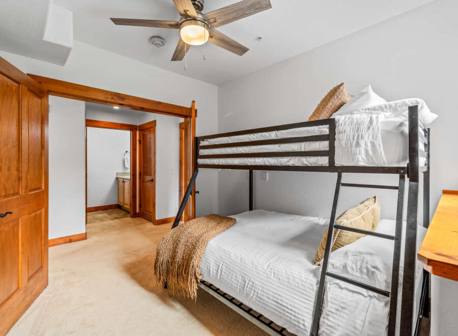 This charming bedroom features a space-saving bunk bed with comfortable white bedding and decorative throw pillows.