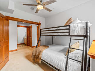 This charming bedroom features a space-saving bunk bed with comfortable white bedding and decorative throw pillows.