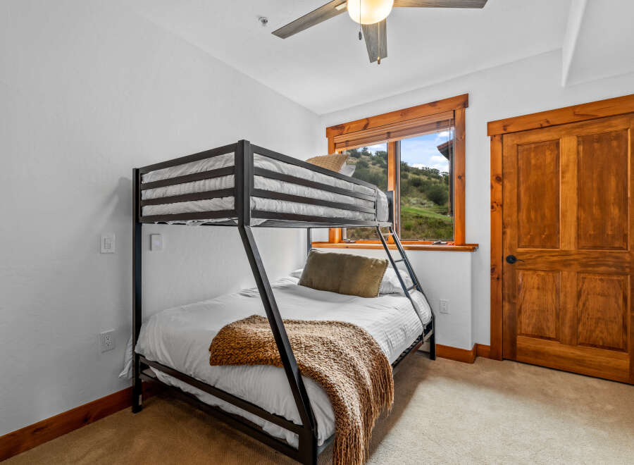 This cozy bedroom features a sturdy black metal bunk bed with white linens, perfect for accommodating guests or children.