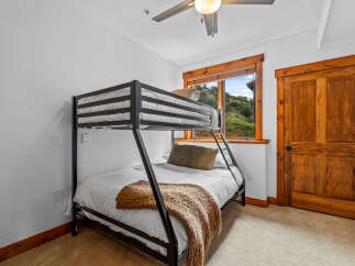 This cozy bedroom features a sturdy black metal bunk bed with white linens, perfect for accommodating guests or children.